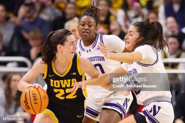 Caitlin Clark of the Iowa Hawkeyes is defended by Paige Mott and Casey Harter of the Northwestern Wildcats during the second half at Welsh-Ryan Arena...