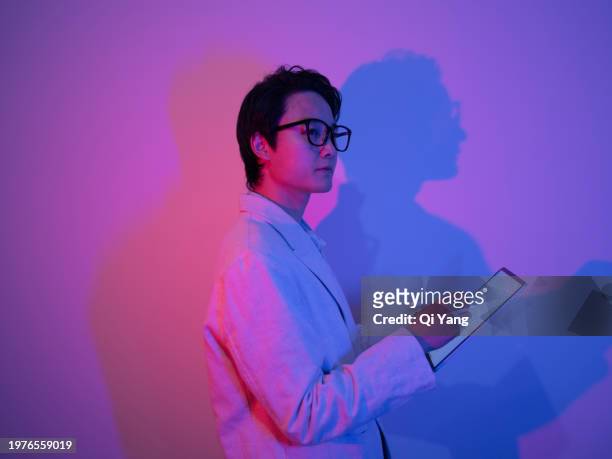 confident asian businessman holding smartphone in neon light - pride gradient stock pictures, royalty-free photos & images