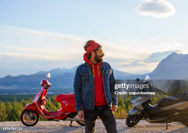 casual man rides scooter on a mountain road - slow life stock pictures, royalty-free photos & images