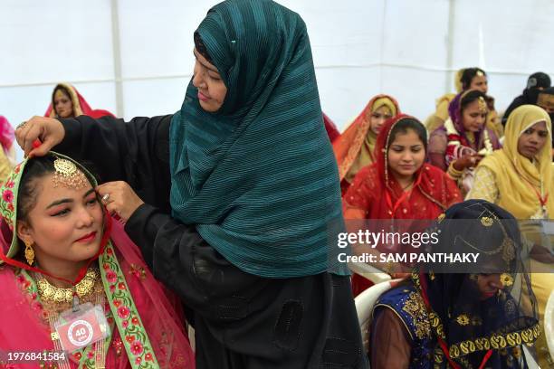 Woman helps a Muslim bride dress up as she with others attend a mass marriage ceremony organised by Gujarat Sarvajanik Welfare trust in Ahmedabad on...