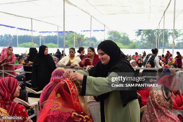 Woman helps a Muslim bride dress up as she with others attend a mass marriage ceremony organised by Gujarat Sarvajanik Welfare trust in Ahmedabad on...