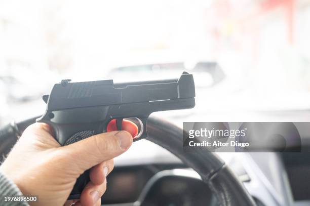 a person holds a gun inside a car - mugger stock pictures, royalty-free photos & images