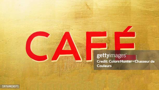 "café" painted in red letters on a gold background. the word was painted on the window of a restaurant in paris, france. sunlight. natural bright colors. - french language stock pictures, royalty-free photos & images