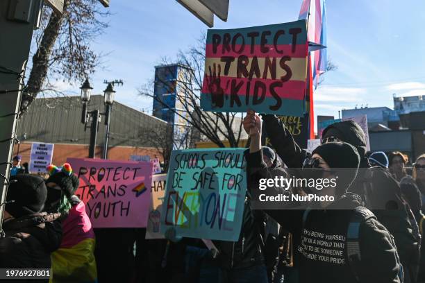 Activists hold placards as hundreds of activists, allies, and members of the transgender community gather at Dr. Wilbert McIntyre Park in Old...