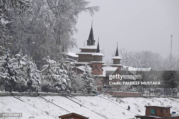 Man walks on the banks of river Jhelum, as snow falls in Srinagar on February 4, 2024.