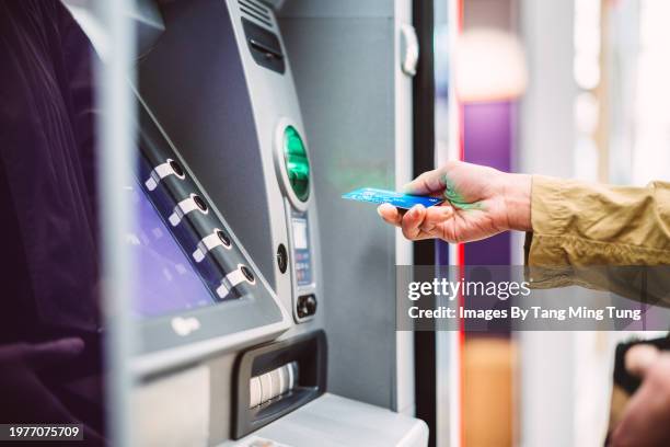 female hand inserting bank card into automatic cash machine (atm) to access bank account services in the city - sportello bancomat foto e immagini stock
