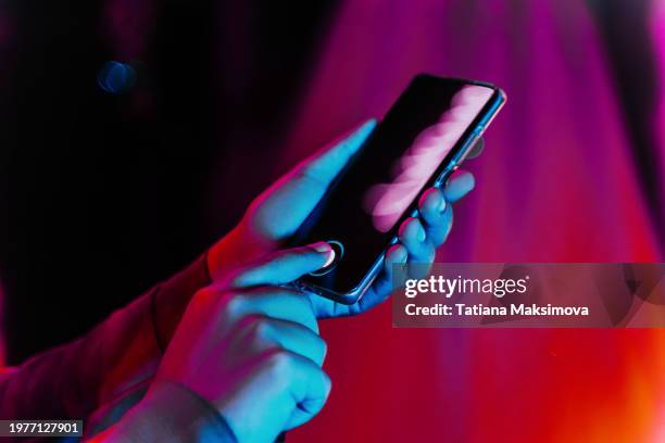 woman’s hands holding phone in neon colors. artificial intelligence concept. - androïde photos et images de collection