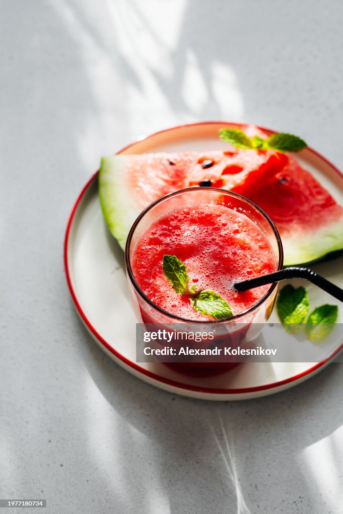 Watermelon smoothies in glass on light table with shadow sunlights. Top view with copy space