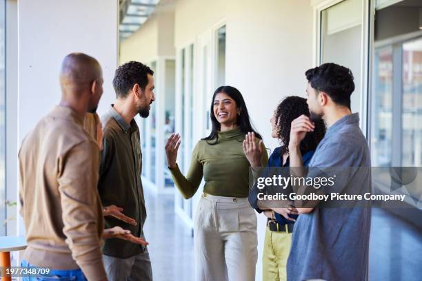 jeune femme d’affaires riante parlant avec des collègues dans un couloir de bureau - groupe multi ethnique photos et images de collection