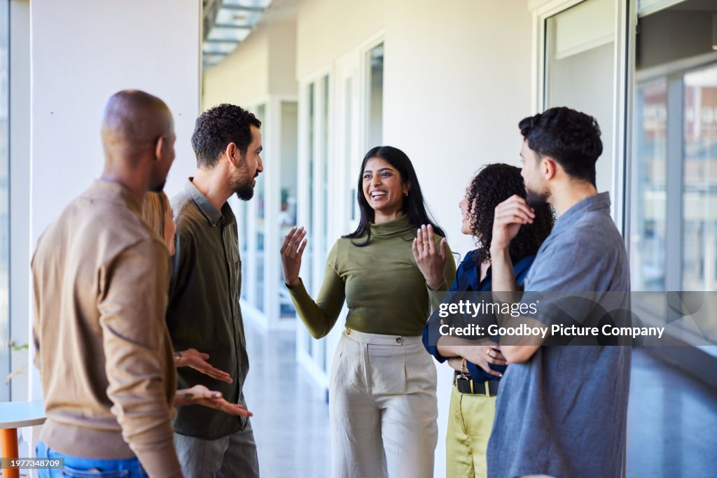 Laughing young businesswoman talking with colleagues in an office hallway