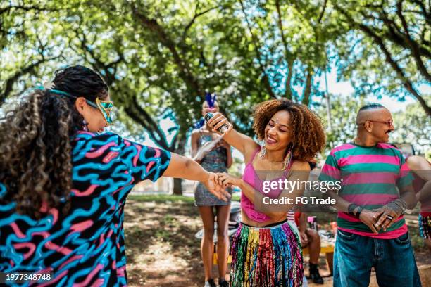 junge frau sprüht sonnencreme auf freund während der karnevalsparty im park - sonnenschutz stock-fotos und bilder