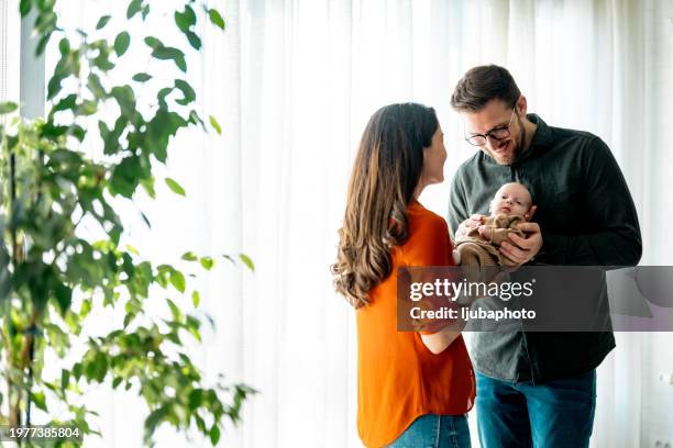 mutter hält schlafendes baby, während der vater mit liebe umarmt. - babypause stock-fotos und bilder