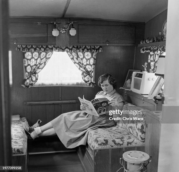 Mildred Wiltshire, wife of a US serviceman, reading a magazine in the couple's caravan near RAF Sculthorpe in Norfolk, July 1955. The site houses...