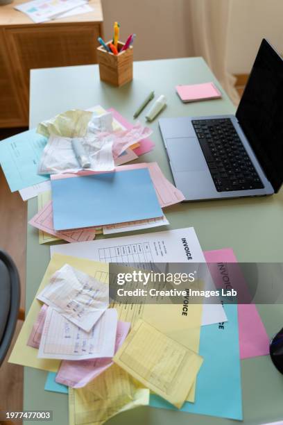 cluttered desk with invoices and laptop open - scattered stock pictures, royalty-free photos & images