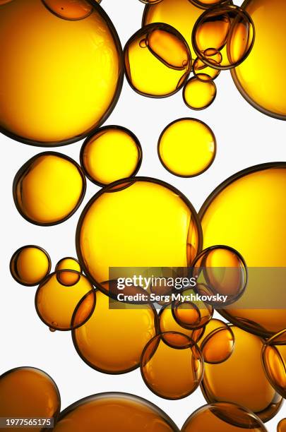 close-up of yellow oil bubbles in water on a white background. - olio di mais foto e immagini stock