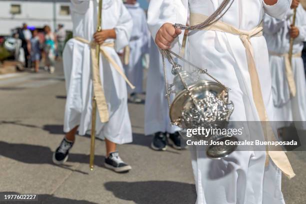 low-angle view of procession participants wearing white tunics carrying a censer during the procession in a manchegan village. - heilige communie stockfoto's en -beelden