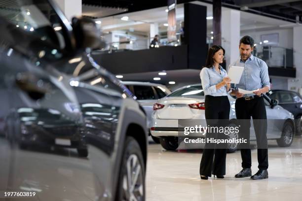 équipe de vendeurs travaillant ensemble dans une salle d’exposition automobile - show room photos et images de collection