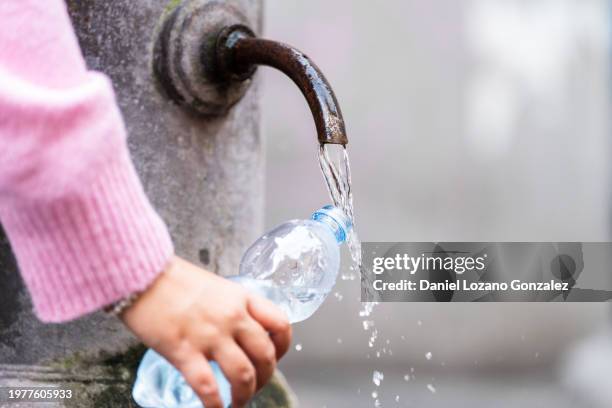 woman charging water in a plastic bottle - fountain stock pictures, royalty-free photos & images