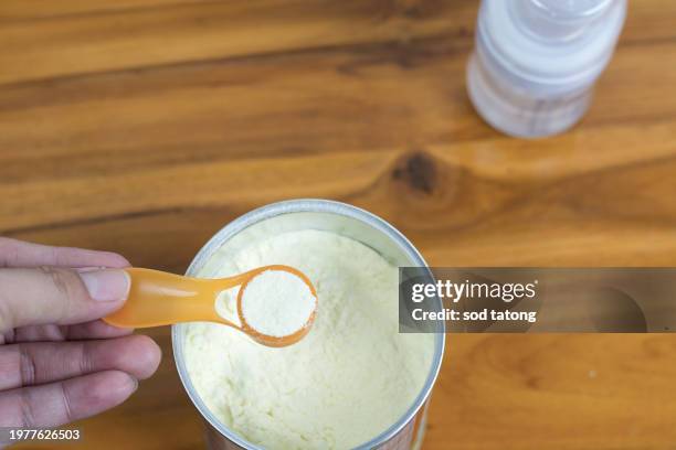 powder milk and blue spoon on light background close-up. milk powder for baby in measuring spoon on can. powdered milk with spoon for baby. baby milk formula and baby bottles - milchpulver stock-fotos und bilder