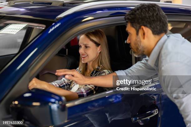 woman checking the car interior while talking to a salesman at the dealership - car dealer window stock pictures, royalty-free photos & images