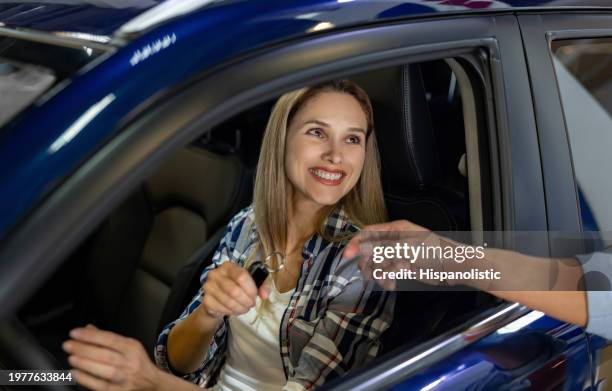 happy woman receiving the keys of her new car at the dealership - car buying stock pictures, royalty-free photos & images