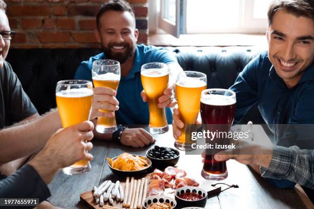 male friends toasting beer in restaurant - artisanal food and drink stockfoto's en -beelden