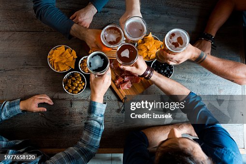 Top view of friends sitting over beer at the table in pub Top view of friends sitting over beer at the table in pub