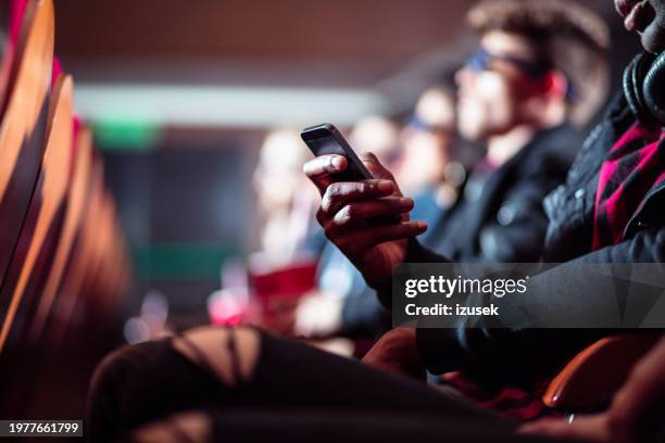 man using mobile phone in movie theater - cinema stock pictures, royalty-free photos & images