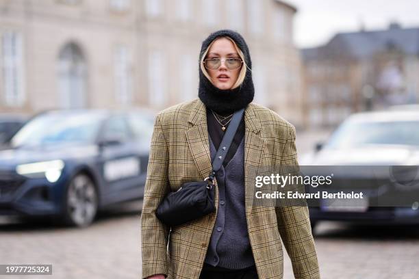 Guest wears a balaclava, sunglasses, a cardigan, a crossbody bag, a beige checkered / checked pattern printed oversized blazer jacket , outside Wood...