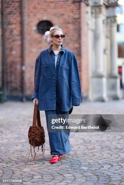 Guest wears a pink floral hair scrunchie, sunglasses, earrings, a blue oversized denim shirt, a blue denim skirt, a brown fluffy bag, red flat shoes...