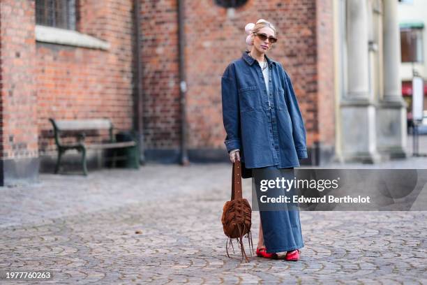 Guest wears a pink floral hair scrunchie, sunglasses, earrings, a blue oversized denim shirt, a blue denim skirt, a brown fluffy bag, red flat shoes...