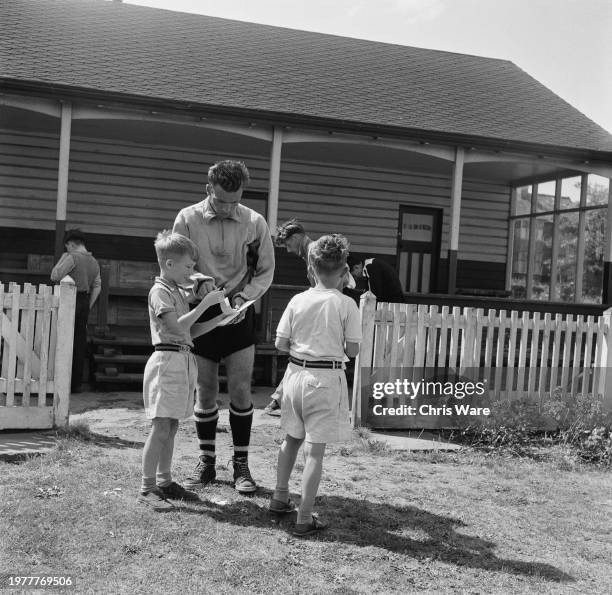 British footballer Ken Hawkes, Luton defender, signs autographs for young boys as he returns to the changing room following a training session ahead...