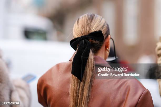 Close-up detail view of a black velvet bow hair scrunchie, and white outside The Garment, during the Copenhagen Fashion Week AW24 on January 31, 2024...