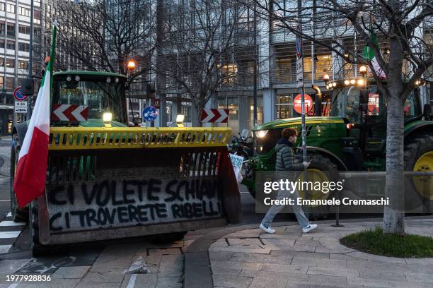 Young man walks past tractors parked in front of Milan Central railway station and Grattacielo Pirelli, one of Region Lombardy's HQ, on February 01,...