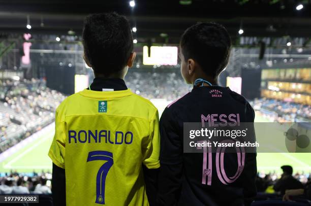 Al-Nassr and Inter Miami fans pose for a photo with the names of Cristiano Ronaldo and Lionel Messi printed on the back of their shirts prior to the...