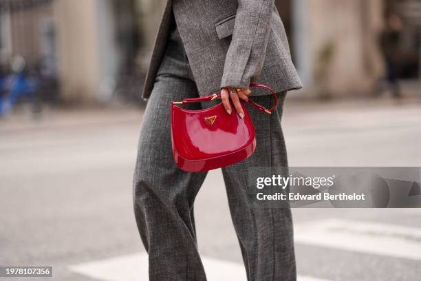 Guest wears sunglasses, a gray oversized blazer jacket , flared pants , a red leather bag from Prada, outside The Garment, during the Copenhagen...