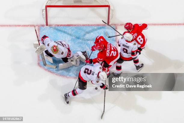 Joonas Korpisalo of the Ottawa Senators follows the play as teammates Artem Zub and Josh Norris battle for the puck with Michael Rasmussen and Andrew...
