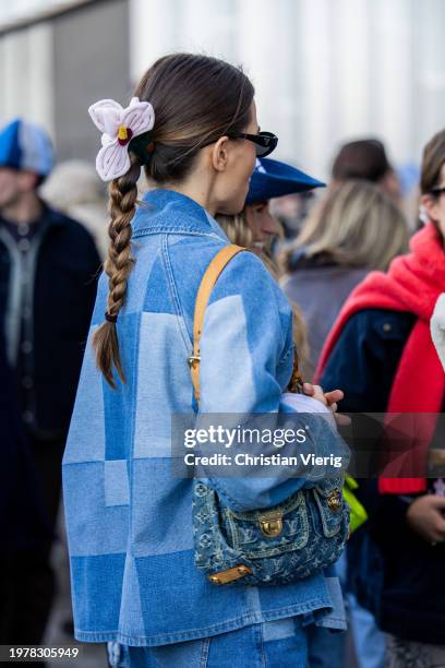 Guest wears floral hair band, oversized checkered denim jacket, Louis Vuitton bag outside Munthe during the Copenhagen Fashion Week AW24 on February...