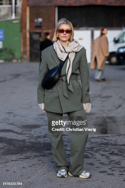 Polly Sayer wears green belted blazer, pants, black bag, grey scarf, gloves outside Gestuz during the Copenhagen Fashion Week AW24 on February 01,...