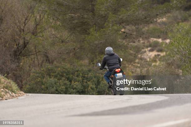 rear view of a man riding motorbike - biker jacket back stock pictures, royalty-free photos & images