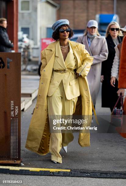 Mona M. Ali wears yellow coat, belted blazer, pants, grey hat outside Gestuz during the Copenhagen Fashion Week AW24 on February 01, 2024 in...