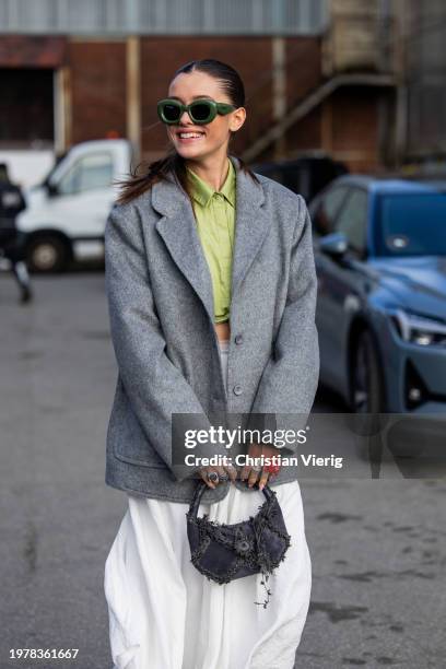 Alexandra Sviridovskaya wears black fringes bag, grey oversized blazer, green sunglasses, white skirt outside Gestuz during the Copenhagen Fashion...