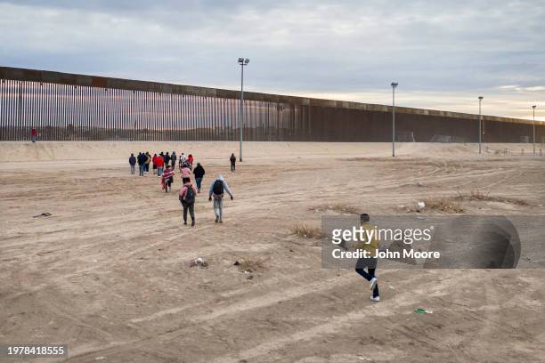 Seen from an aerial view, immigrants run towards the U.S.-Mexico border wall after crossing the Rio Grande into El Paso, Texas on February 01, 2024...