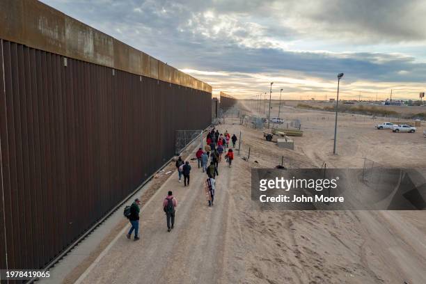 Seen from an aerial view, immigrants walk along the U.S.-Mexico border wall after crossing the Rio Grande into El Paso, Texas on February 01, 2024...