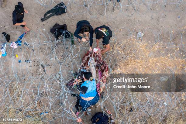 Seen from an aerial view, people pass through razor wire after crossing the U.S.-Mexico border into El Paso, Texas on February 01, 2024 from Ciudad...