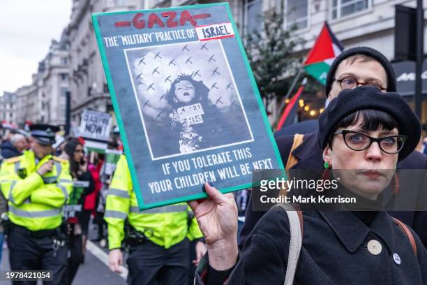 Pro-Palestinian protester is pictured holding an amended copy of a 1937 propaganda poster from the Spanish Civil War before a march to call for an...