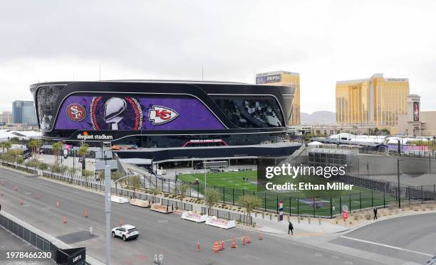 An exterior view shows an image of the Lombardi Trophy, team logos and signage for Super Bowl LVIII as workers paint a Super Bowl LVIII logo on the...