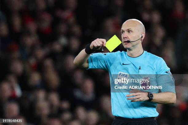 Referee Anthony Taylor shows a yellow card to Arsenal's Brazilian defender Gabriel Magalhaes during the English Premier League football match between...