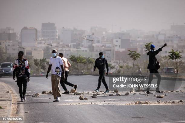 Protesters block a road with bricks during demonstrations called by the opposition parties in Dakar on February 4 to protest against postponement of...