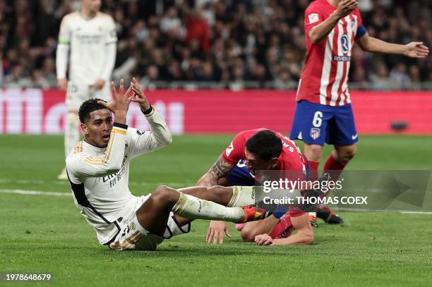 Real Madrid's English midfielder Jude Bellingham and Atletico Madrid's Montenegrin defender Stefan Savic react after a fall during the Spanish league...